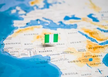 Part of world map with African continent shown prominently. Nigerian flag sticks out of the map to mark where the country is.