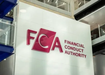 The logo and name of the Financial Conduct Authority (FCA) are displayed on a large white wall inside a modern office building with glass and metal features, reflecting its oversight roles in sectors such as Crypto UK.