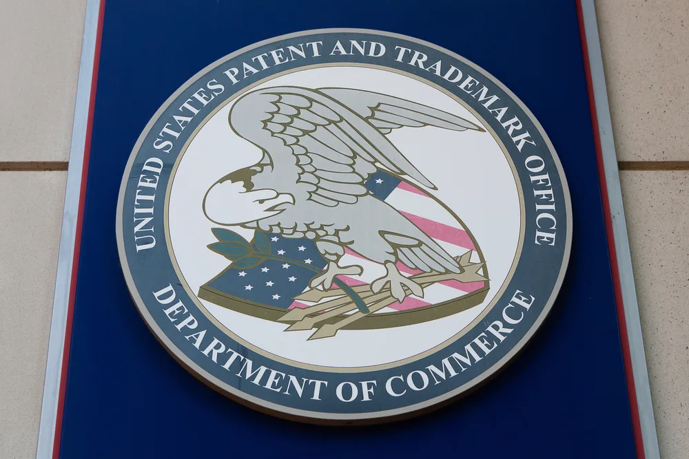 The official seal of the United States Patent and Trademark Office, featuring a bald eagle with a flag shield holding a branch and arrows, surrounded by a blue ring with the agency’s name and “Department of Commerce.”.