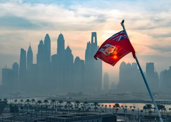 Maritime flag of Bermuda flutters in front of outline of city skyline in article about the take-up of crypto in Bermuda.