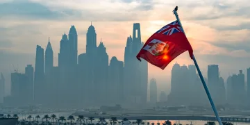 Maritime flag of Bermuda flutters in front of outline of city skyline in article about the take-up of crypto in Bermuda.