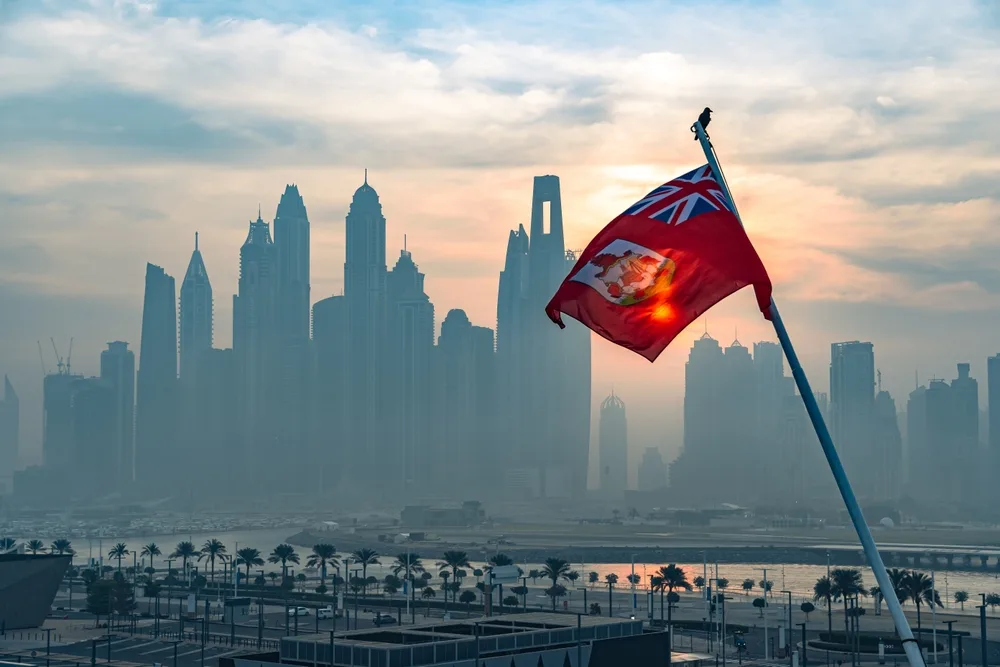 Maritime flag of Bermuda flutters in front of outline of city skyline in article about the take-up of crypto in Bermuda.
